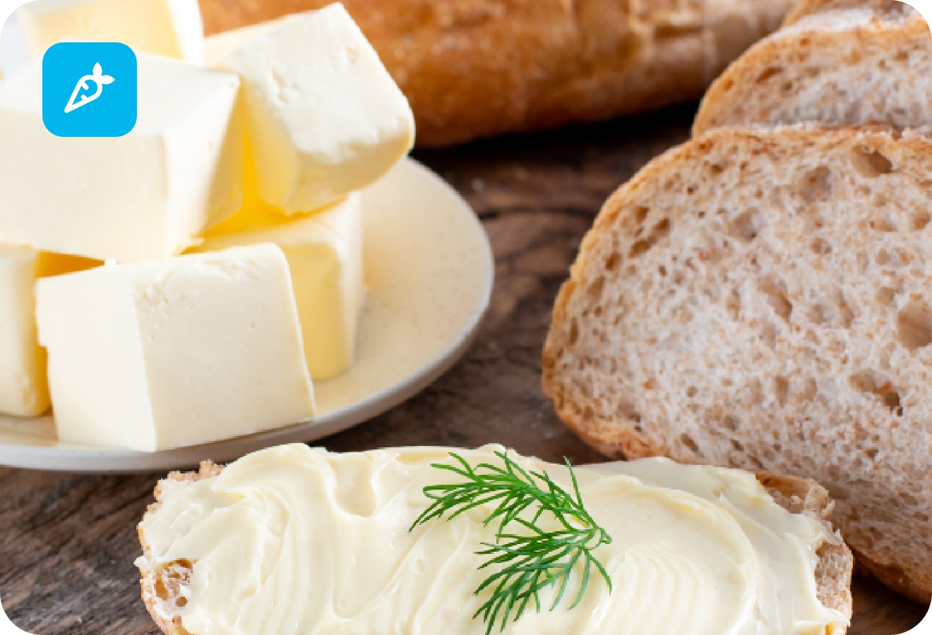 Frisches Bauernbrot mit Butter und Dill, daneben Butterwürfel auf Teller