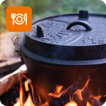 Dampfender Dutch Oven auf von Holzkohle gespeister offener Flamme.