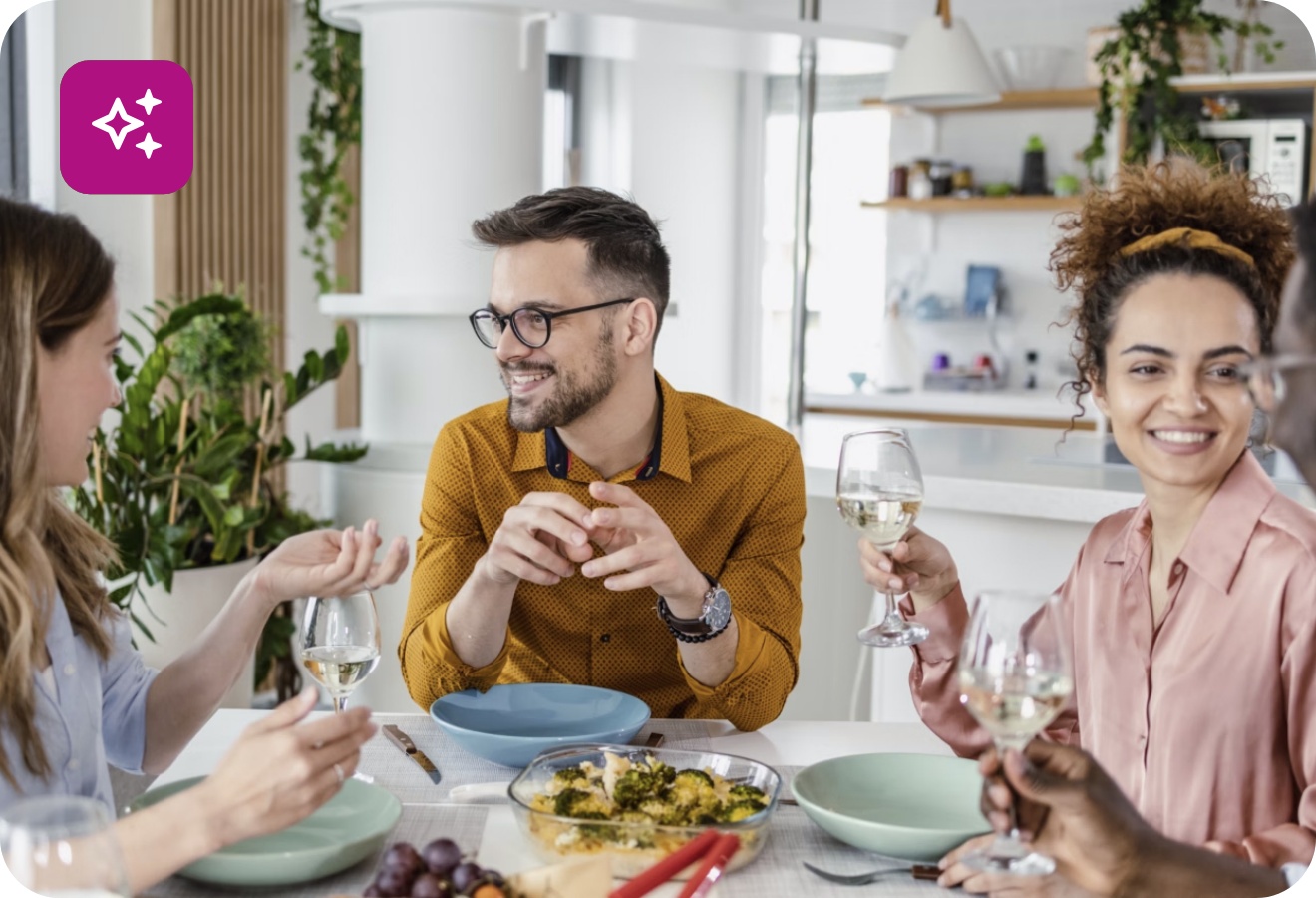 Gruppe von Gästen genießt ein gemeinsames Essen und Wein am gedeckten Tisch.