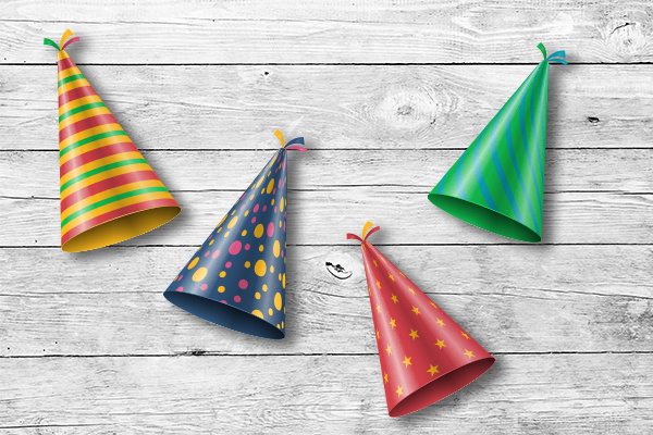 Vier bunte Partyhütchen auf einem Untergrund aus Holz für die Silvesterfeier.