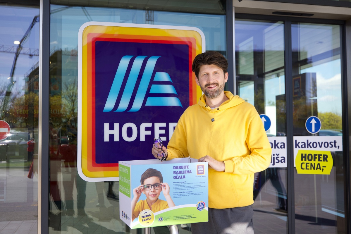 Tomaž Mihelič pred Hofer trgovino s škatlo za rabljena očala