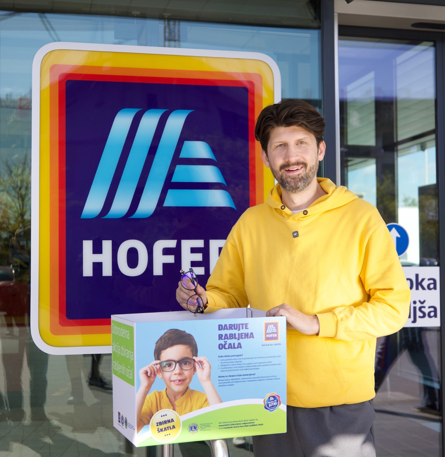 Tomaž Mihelič pred Hofer trgovino s škatlo za rabljena očala