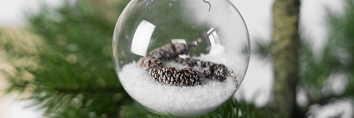 Nadelbaum im Hintergrund, im Vordergrund ist eine selbstgestaltete Glaskugel zu sehen