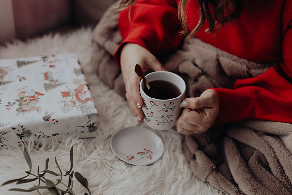 Tee wird gehalten neben einem Geschenk