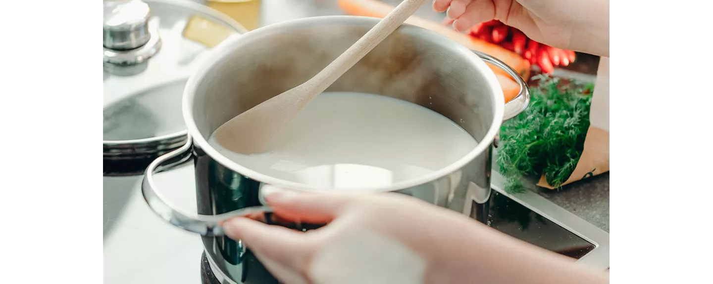 Una persona calentando leche para eliminar las manchas de vino