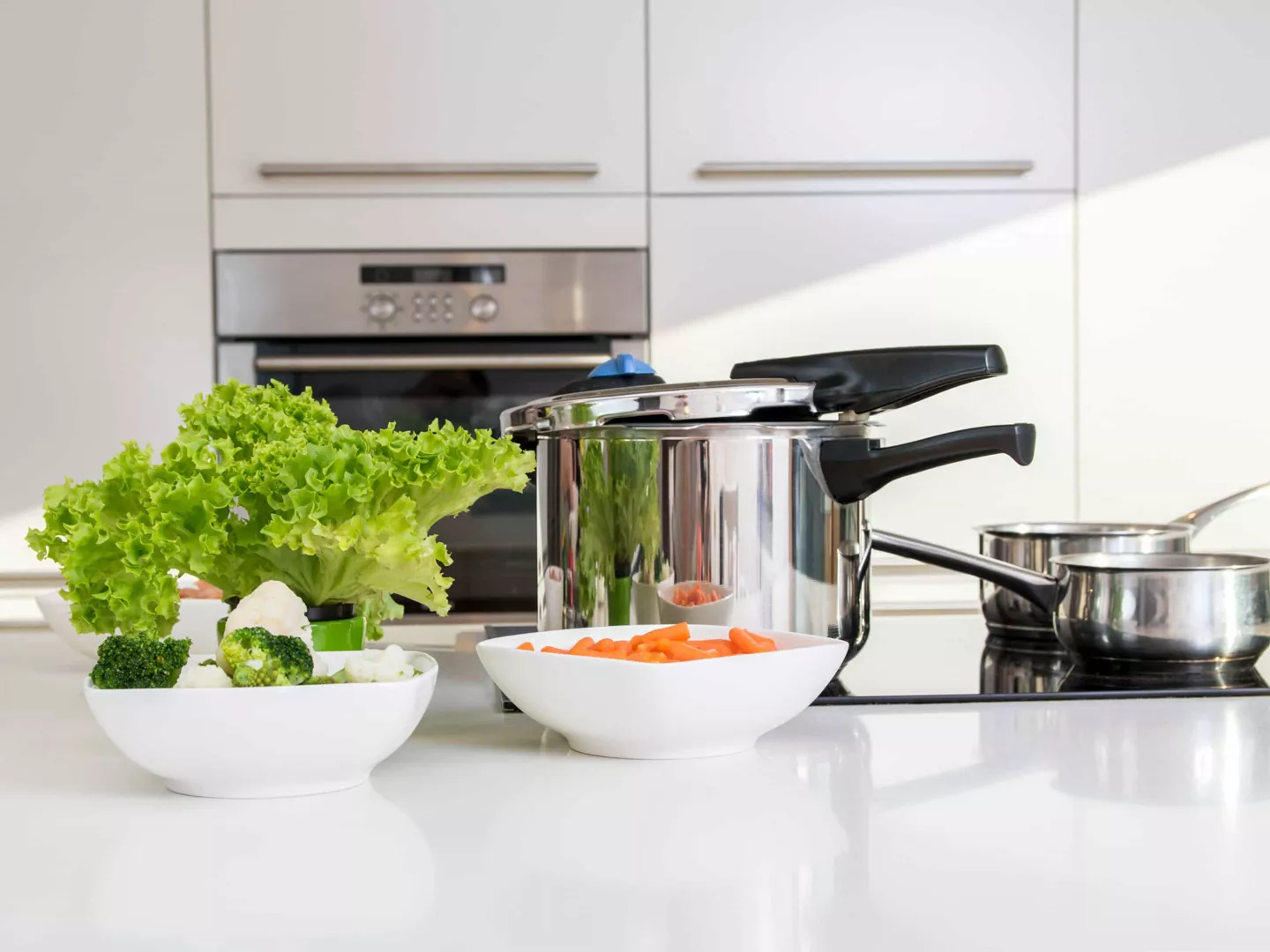 Isla cocina con olla express y hortalizas cocidas 