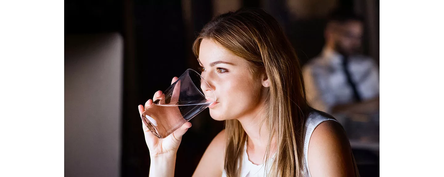Mujer bebiendo agua para mantenerse hidratada durante el ciclo menstrual