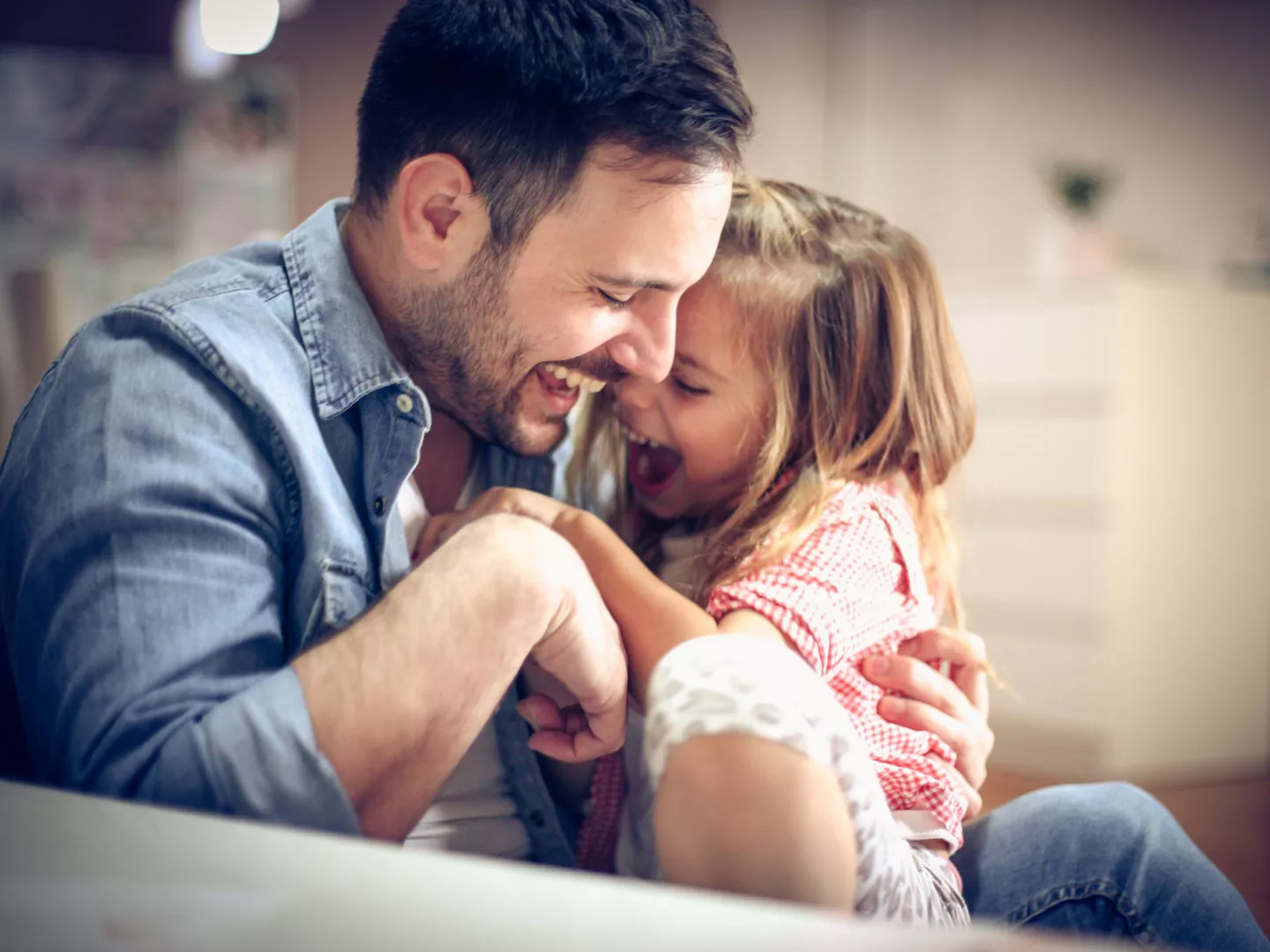 Padre e hija haciéndose cosquillas y riendo a carcajadas