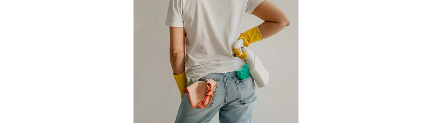 Persona con guantes de limpieza sosteniendo un pulverizador y un paño, lista para usar amoniaco para limpiar