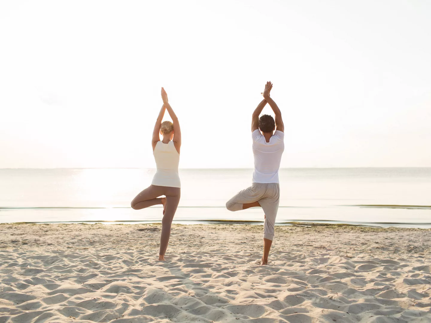 Pareja practicando yoga playa