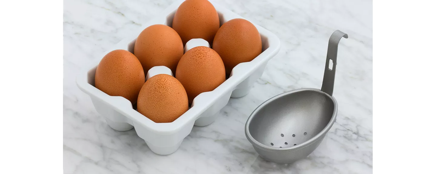 Huevos enteros y un separador de claras colocado encima de la mesa