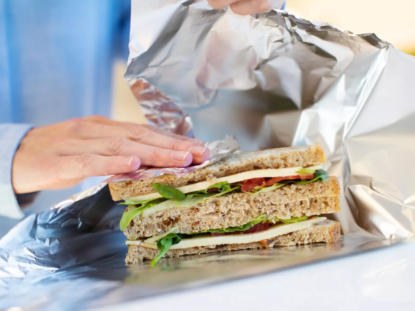 Persona envolviendo sándwich papel de aluminio