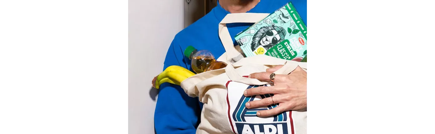 Person hält eine volle Einkaufstasche im Arm.