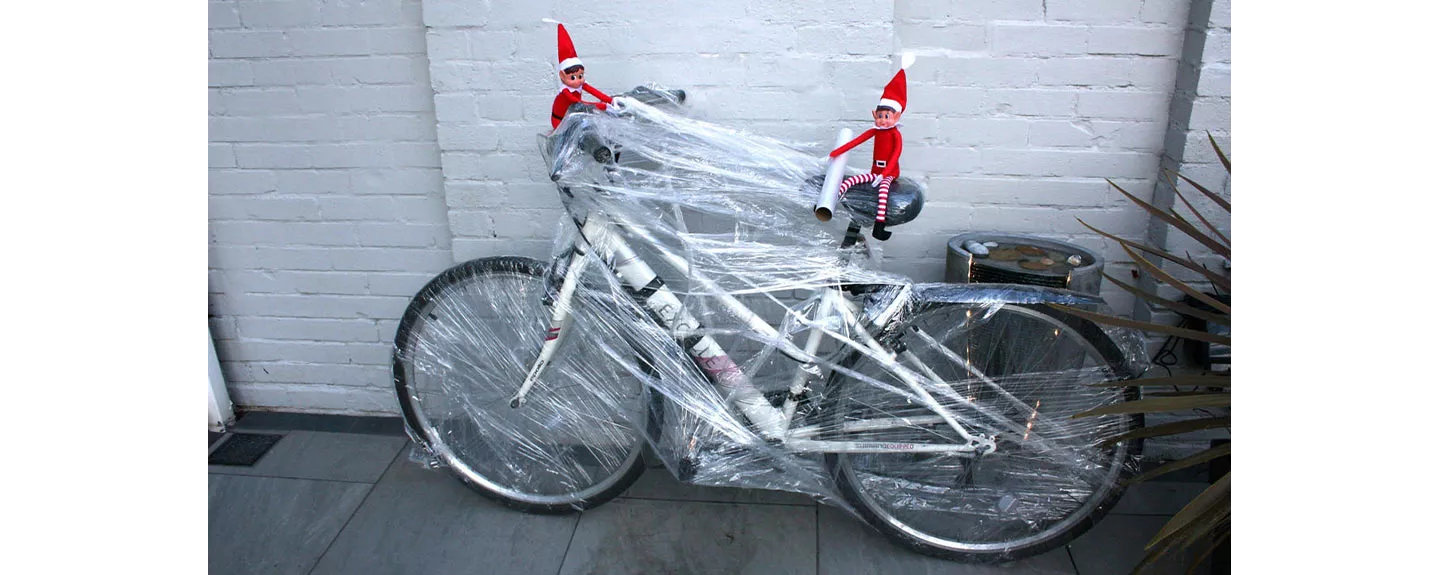 elfos traviesos de Navidad envolviendo una bici con film 