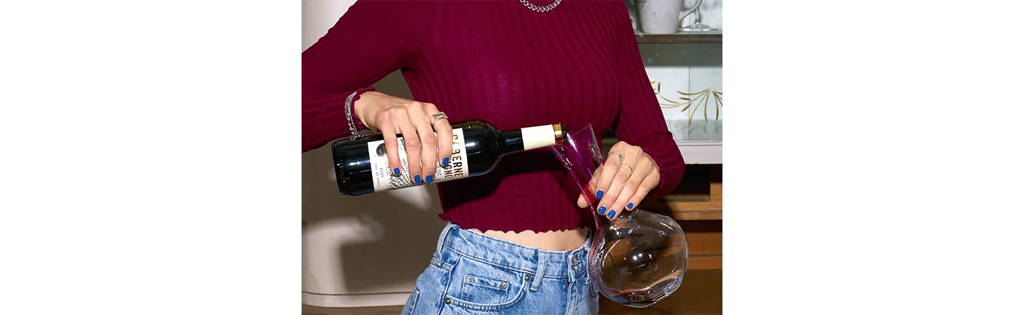 Frau füllt Wein in Dekanter.