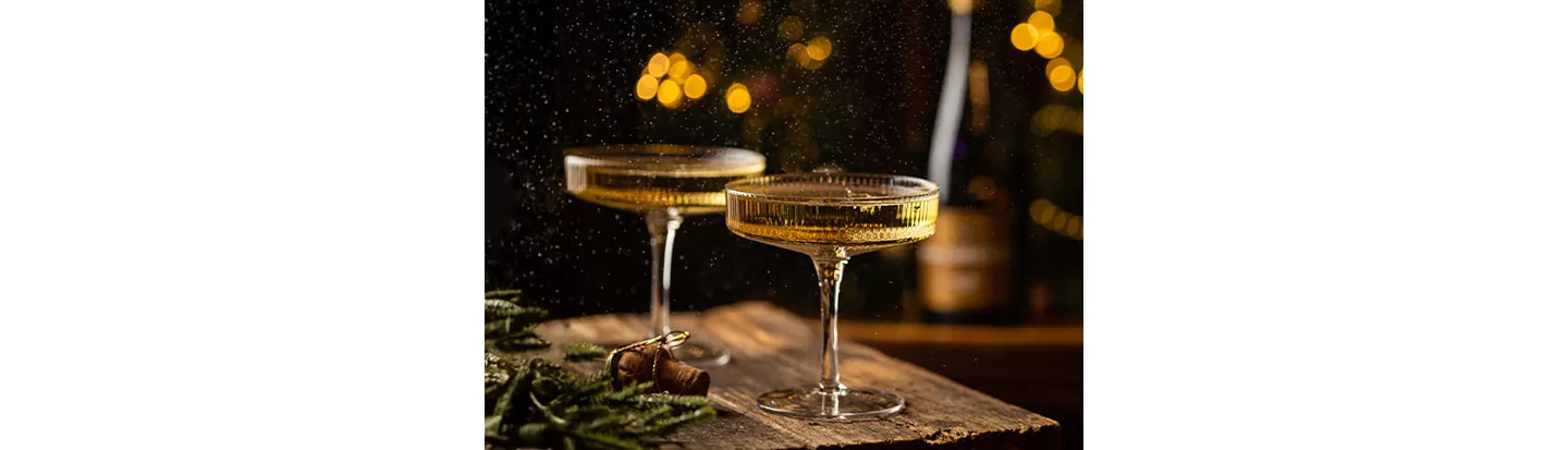Copas de espumoso sobre una mesa decorada con adornos navideños, ilustrando las diferencias entre cava y champán