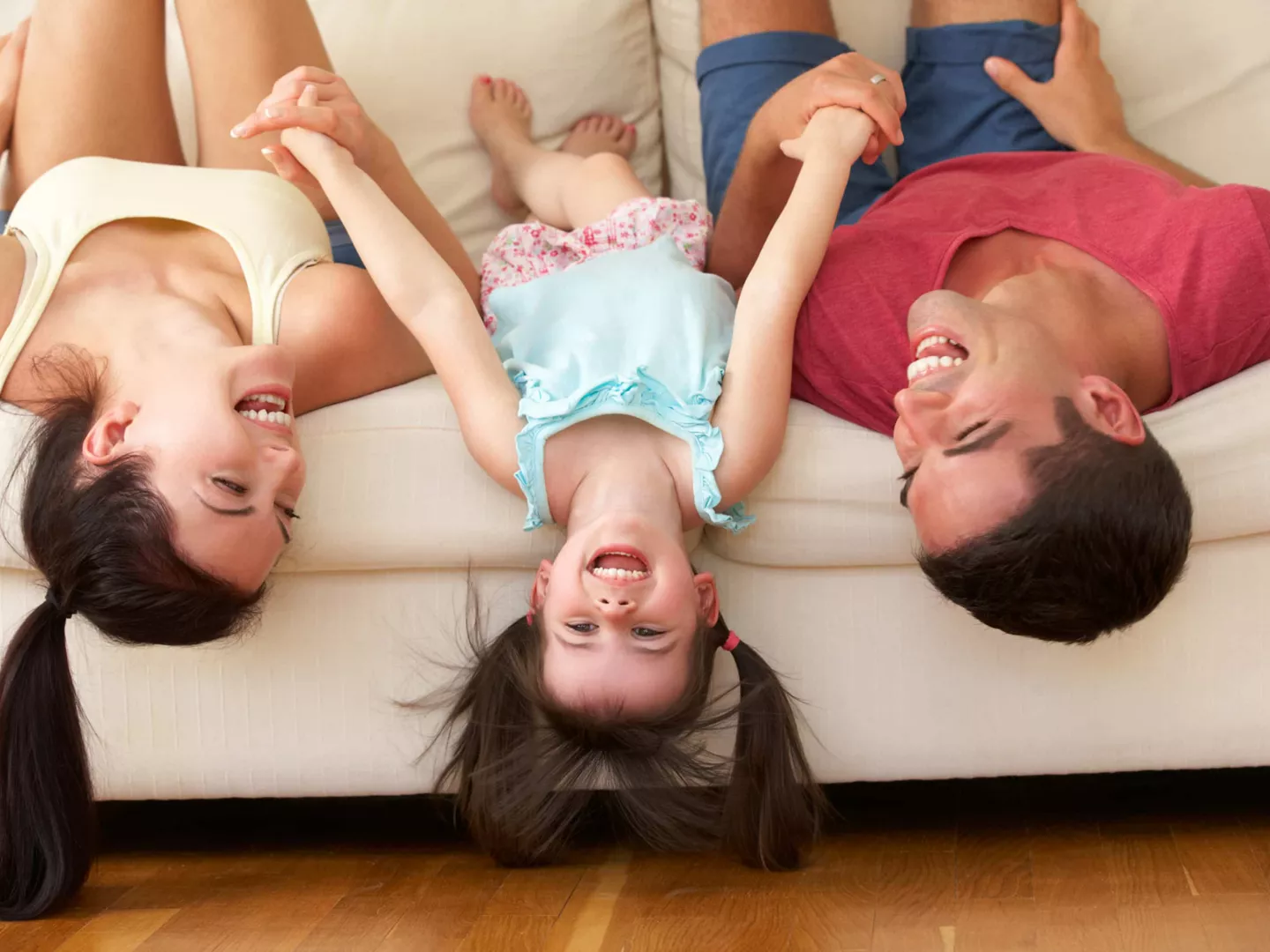 Familia riendo cabeza del revés en un sofá