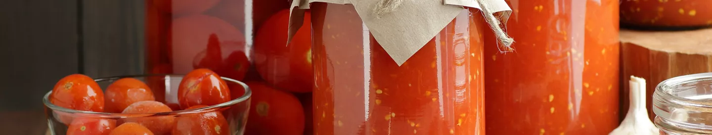 Tarros de tomate en conserva casero junto a tomates frescos