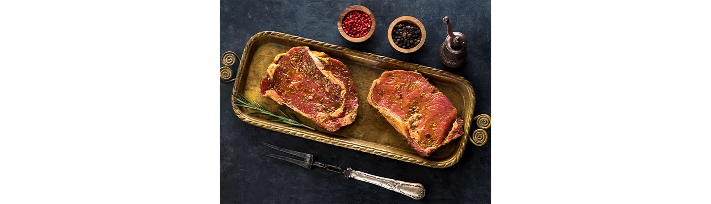 Filetes de carne macerada con hierbas y especias sobre bandeja decorativa