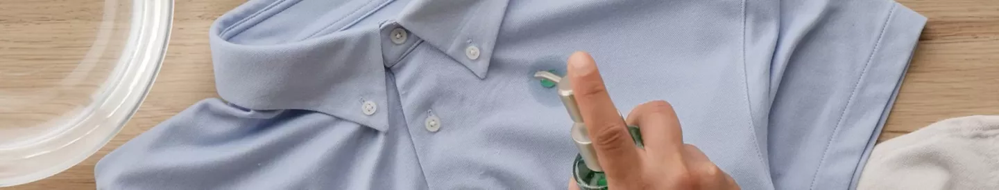 Mano aplicando jabón lavavajillas mancha camisa