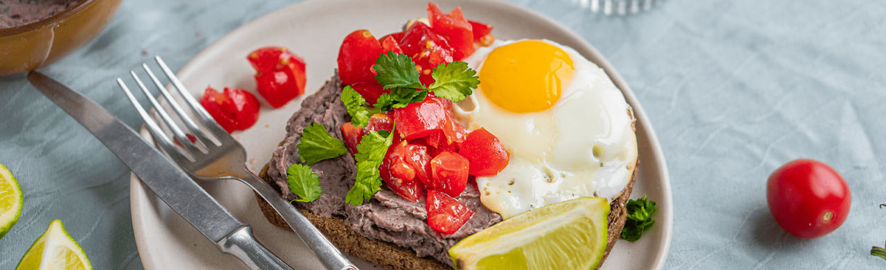 Volkoren toast met zwarte bonenpuree, tomaatjes en een eitje