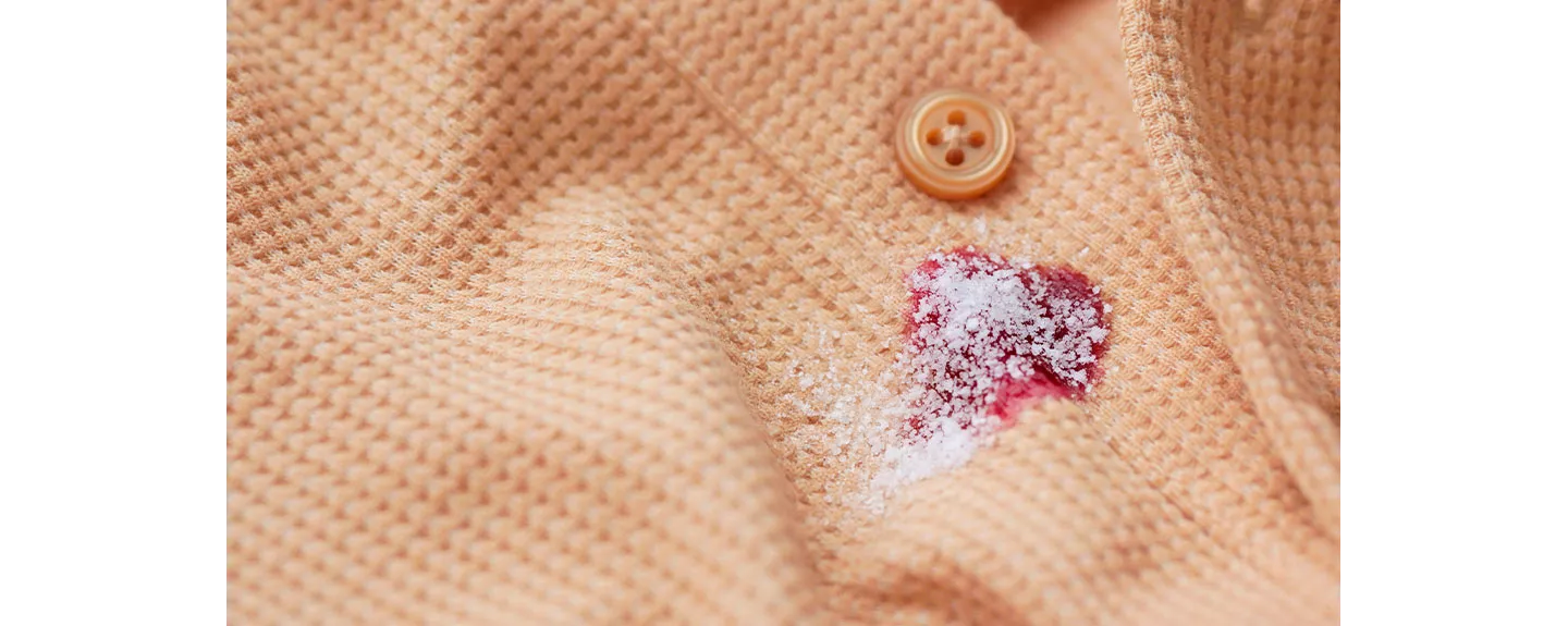 Una mancha de vino tinto sobre una camisa, con sal aplicada para eliminar la mancha