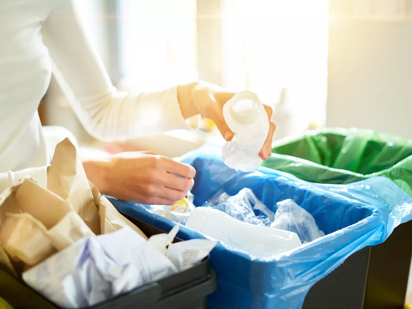 Persona poniendo botella cubos basura reciclaje