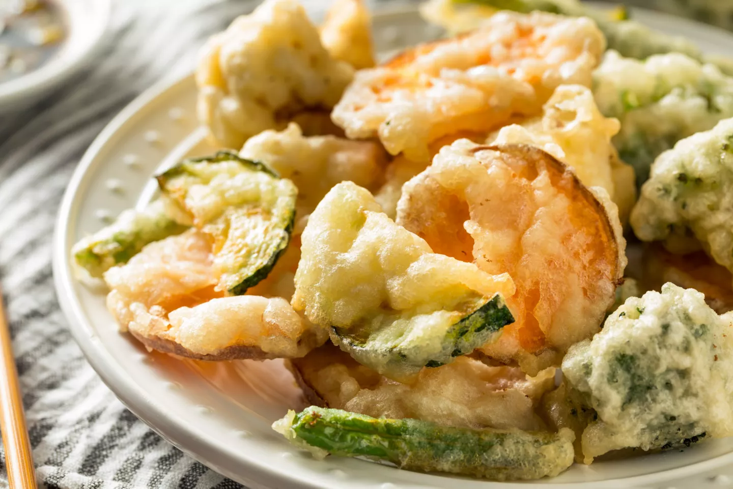 Verduras rebozadas en tempura crujiente servidas en plato blanco