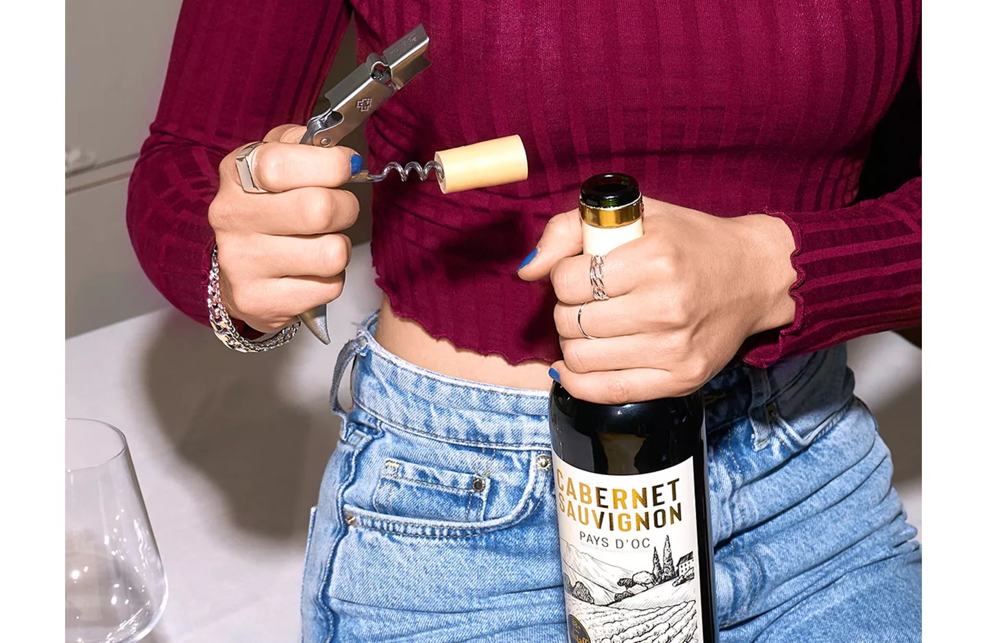 Frau öffnet Wein mit einem Korkenzieher.