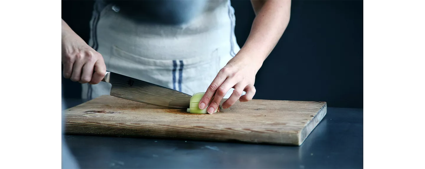 Una persona usando un cuchillo cebollero para cortar en brunoise