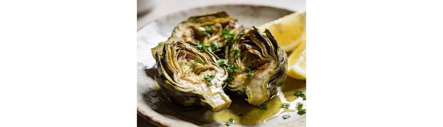 Alcachofas servidas en plato con limón y perejil