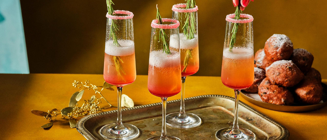Feestcocktail met cava en cranberrysiroop en rozemarijn 