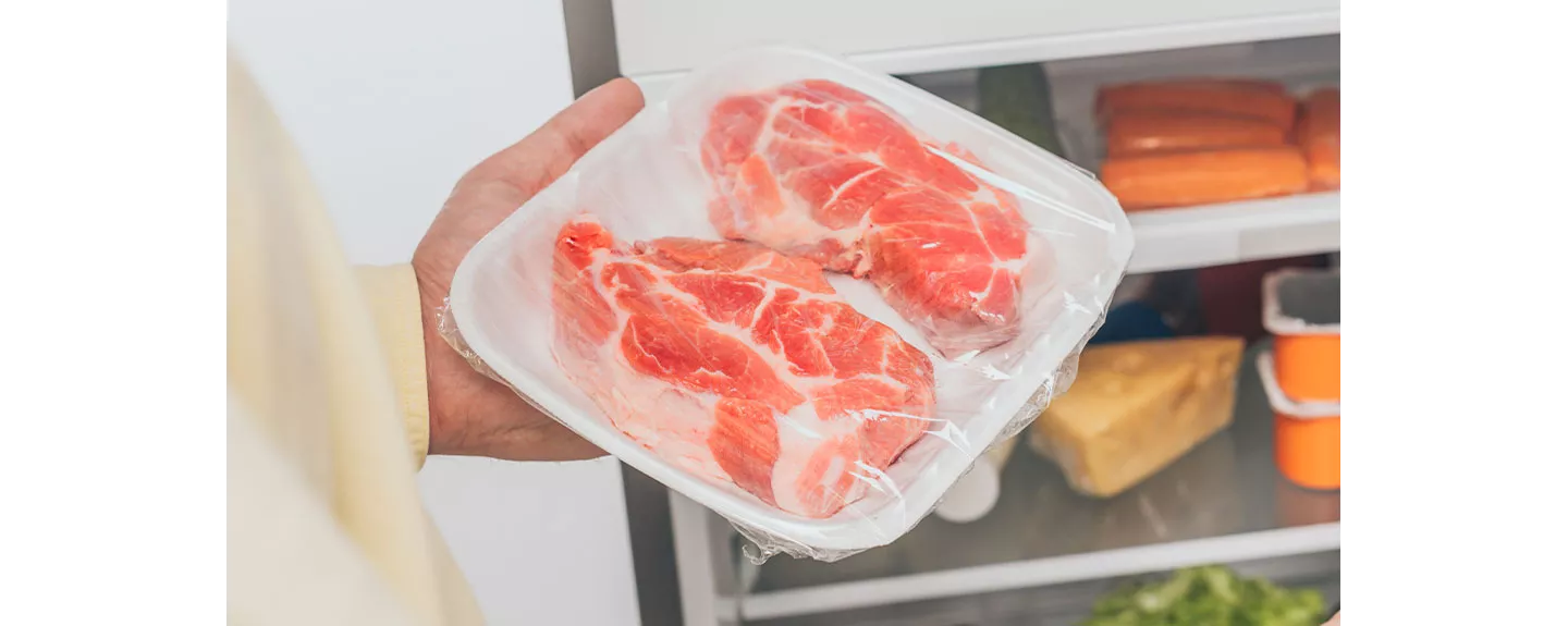 Carne envuelta en bandeja dentro de la nevera para reposar antes de cocinar