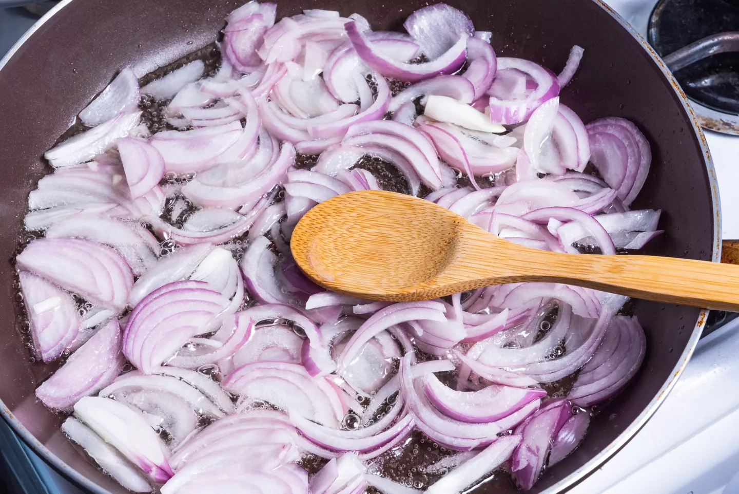 Cebolla morada cortada en juliana cocinándose en una sartén