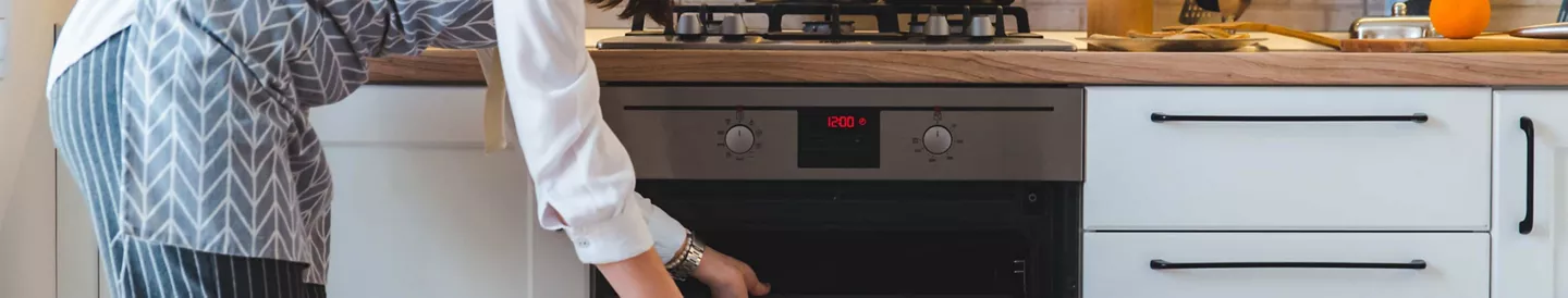 Mujer abriendo el horno para limpiarlo