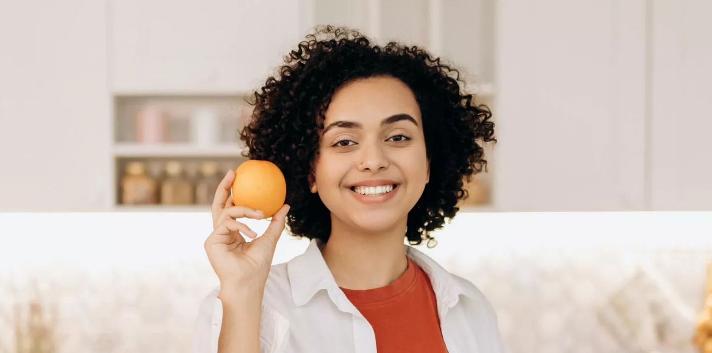 Mujer sujetando naranja, buena para aumentar la serotonina