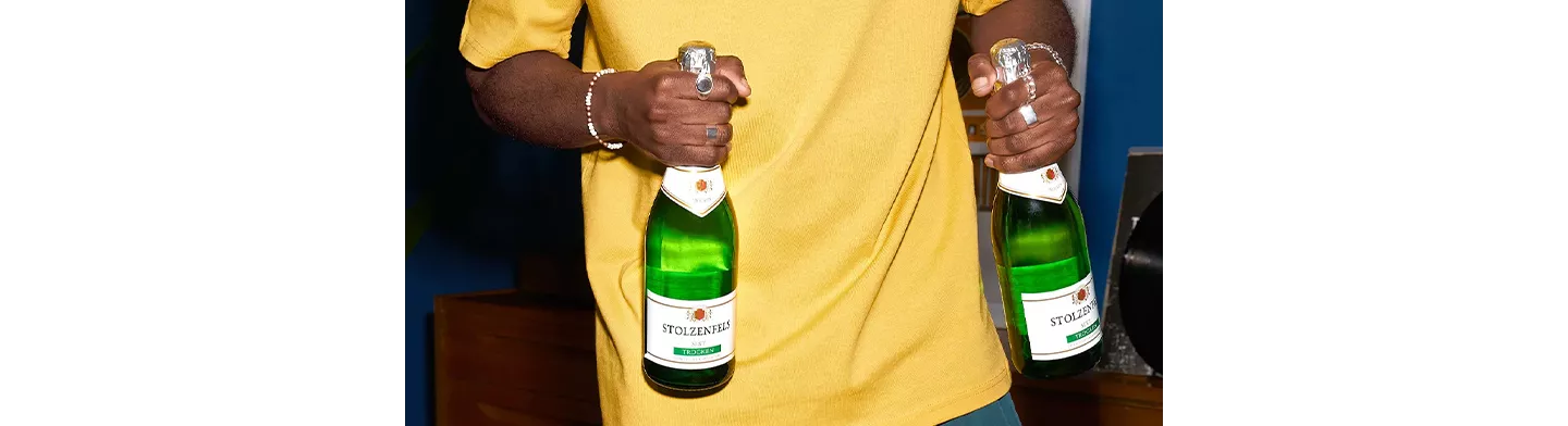 Mann hält zwei Flaschen Sekt in seinen Händen.