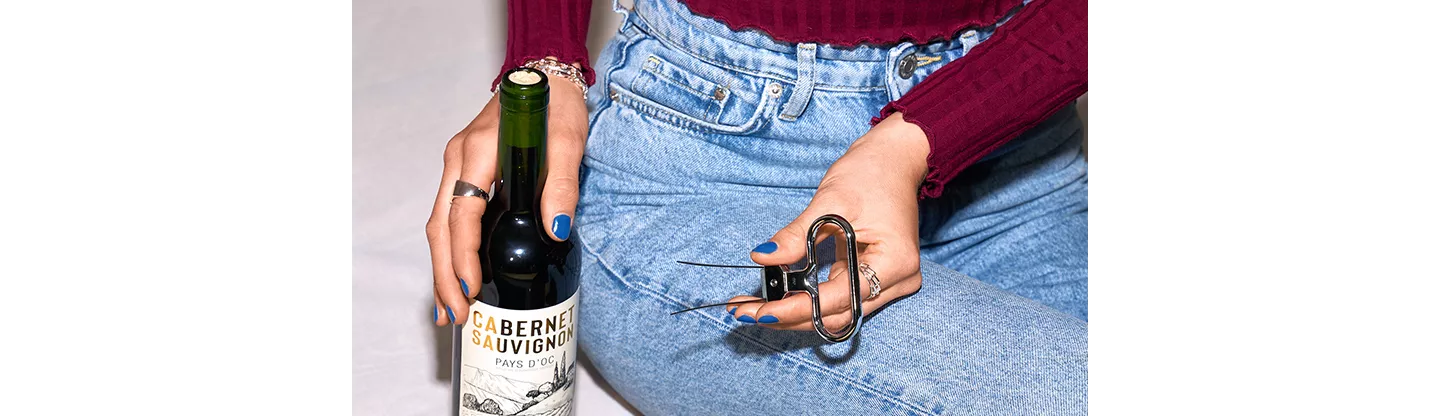 Person mit Weinflasche und Korkenentferner