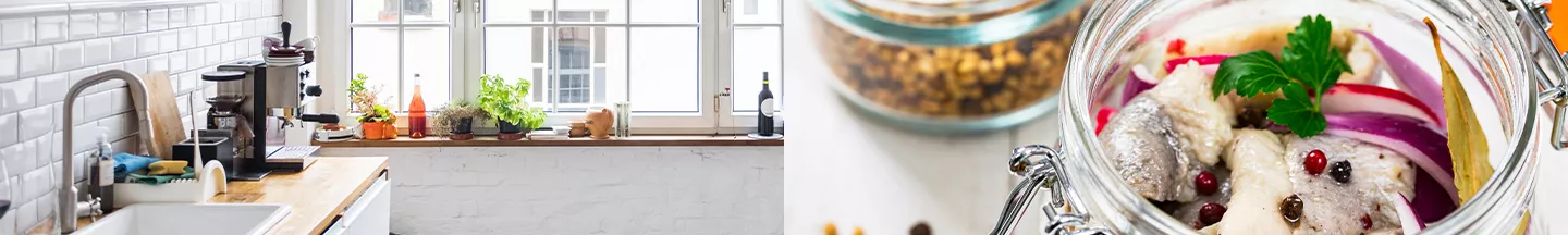 Küchenzeile mit Kaffeemaschine am Fenster und Einmachgläser mit roten Zwiebeln und Fisch.