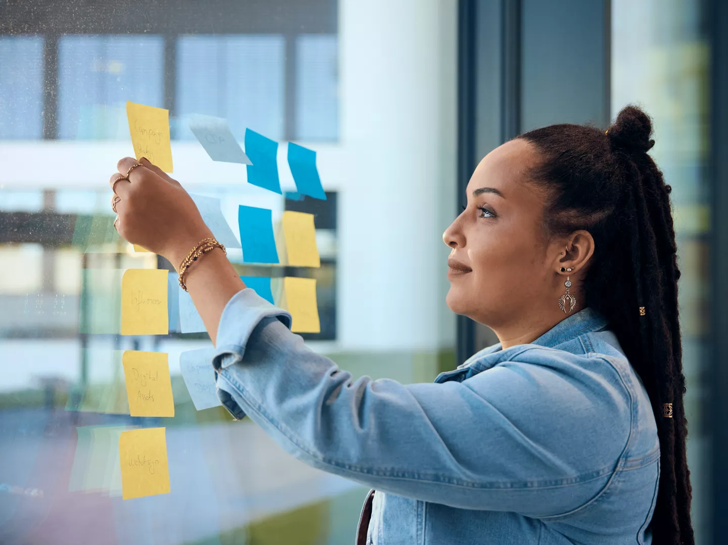 Eine ALDI Mitarbeiterin klebt Post-Its an ein Fenster