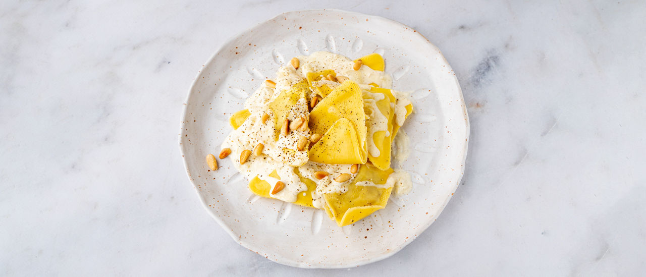 Verse gevulde pasta met eekhoorntjesbrood, roomsaus en pijnboompitjes 
