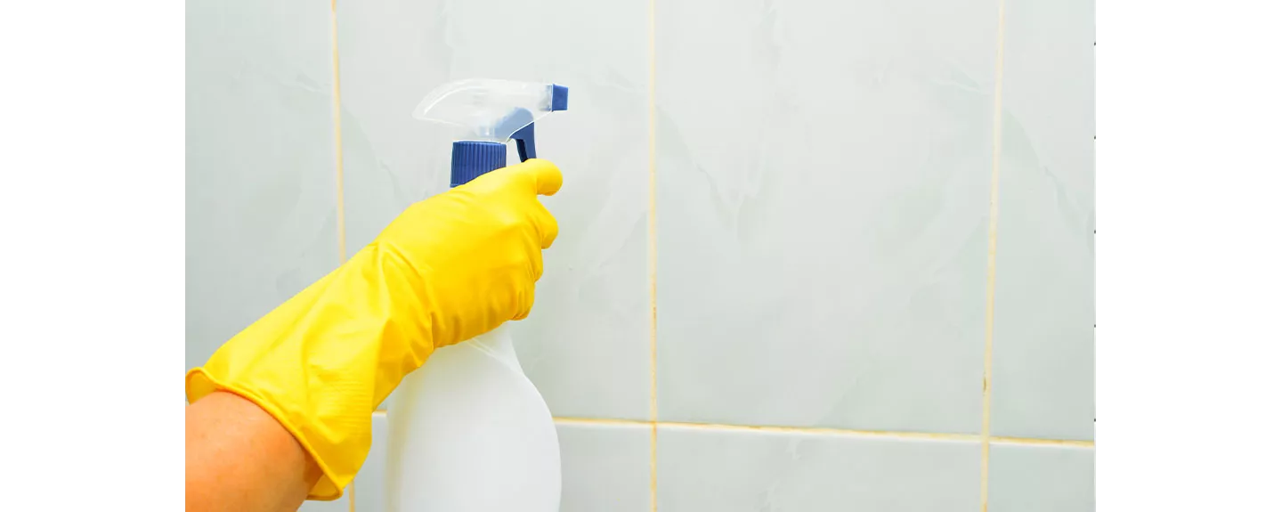 Una persona quitando el moho de la pared de la ducha