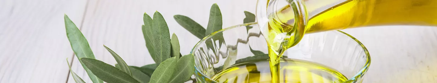Mano vertiendo aceitera con aceite de oliva virgen en recipiente