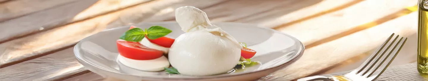 Mozzarella acompañada de rodajas de tomate y albahaca, resaltando sus diferencias con la burrata