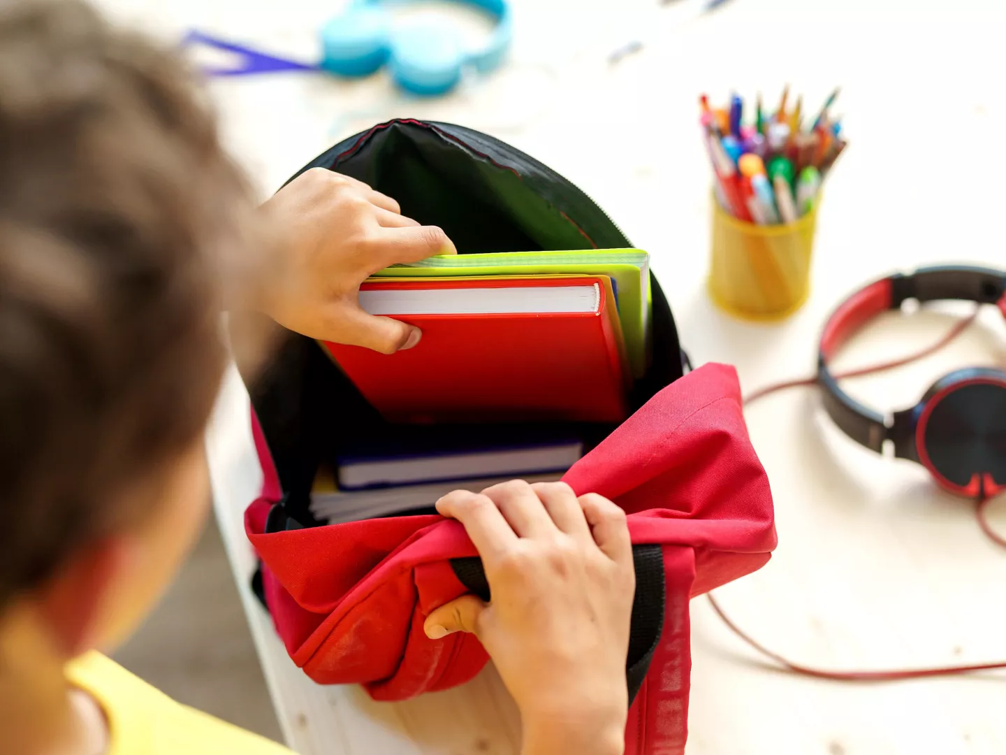 Niño introduciendo material escolar interior mochila