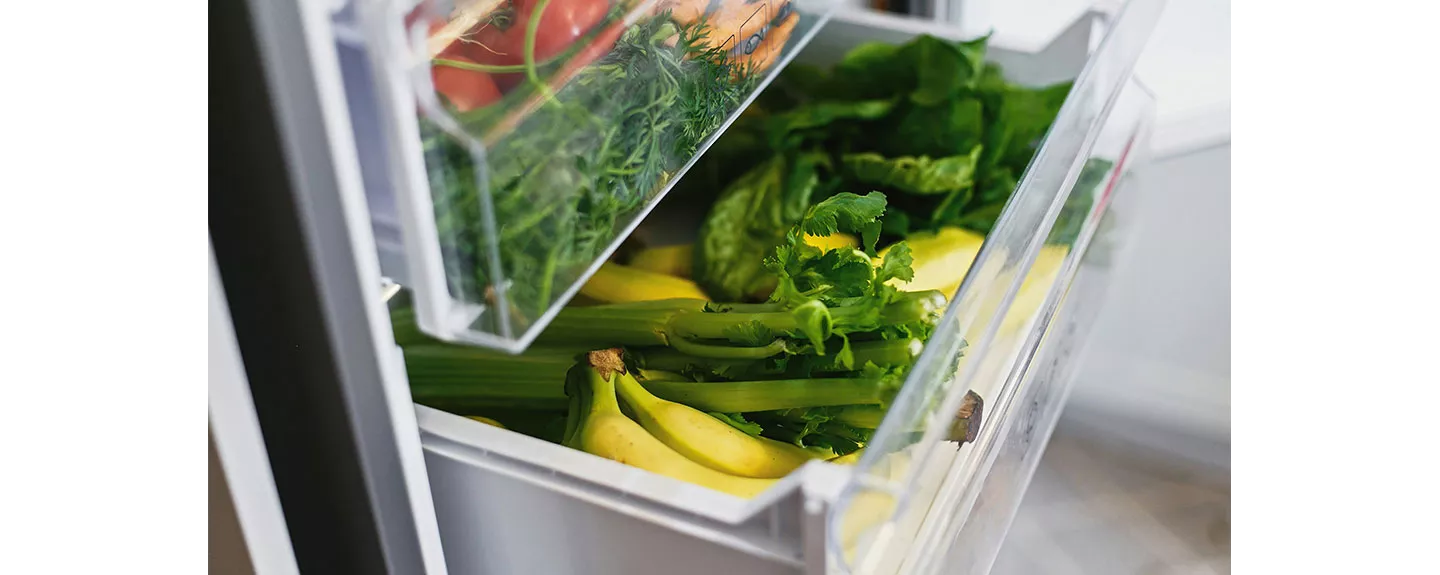 Cajón inferior de una nevera con frutas y verduras, organizados para una mejor conservación