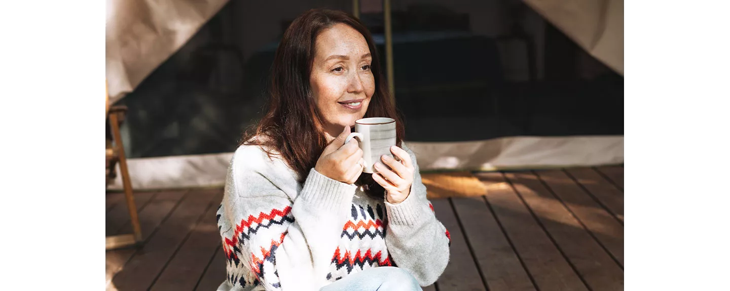 Una mujer tomando una bebida caliente que puede generar una sensación de relajación