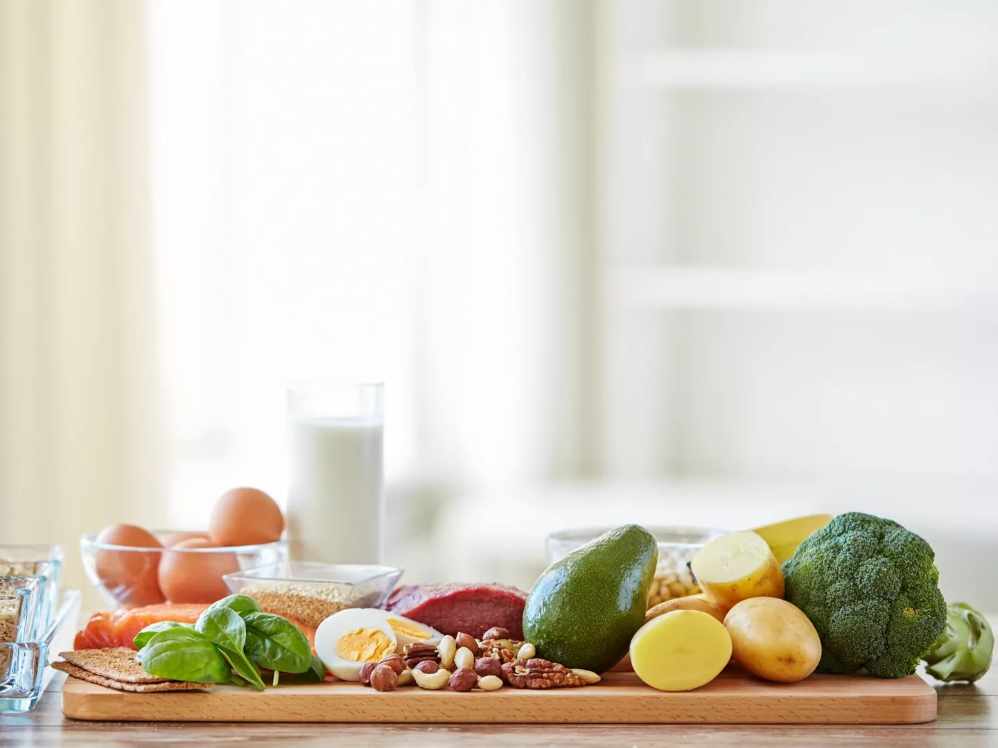 Tabla con alimentos saludables como aguacate, huevo, frutos secos y verduras, ideales para cuidar el pelo.