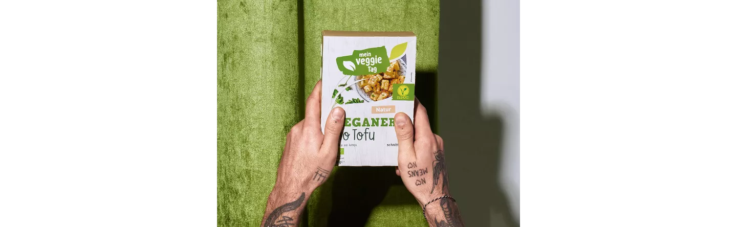 Person hält eine Packung veganen Bio-Tofu in die Kamera.
