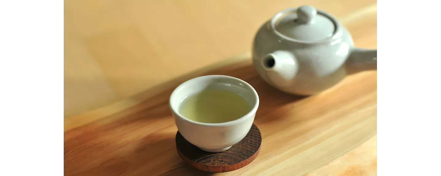 Taza de té verde sobre la mesa, bebida rica en antioxidantes naturales beneficiosos para la salud celular.